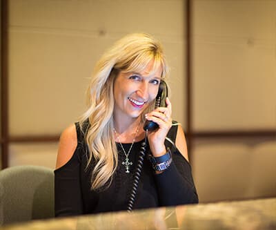 Blonde woman answering the phone, answering questions about dental manager sponsorship